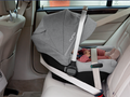 Cadeira auto PIPA Next instalada no carro, contra a marcha, com um bebé dentro e a capota puxada para baixo, oferecendo sombra e proteção.
