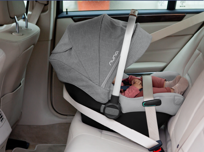 Cadeira auto PIPA Next instalada no carro, contra a marcha, com um bebé dentro e a capota puxada para baixo, oferecendo sombra e proteção.