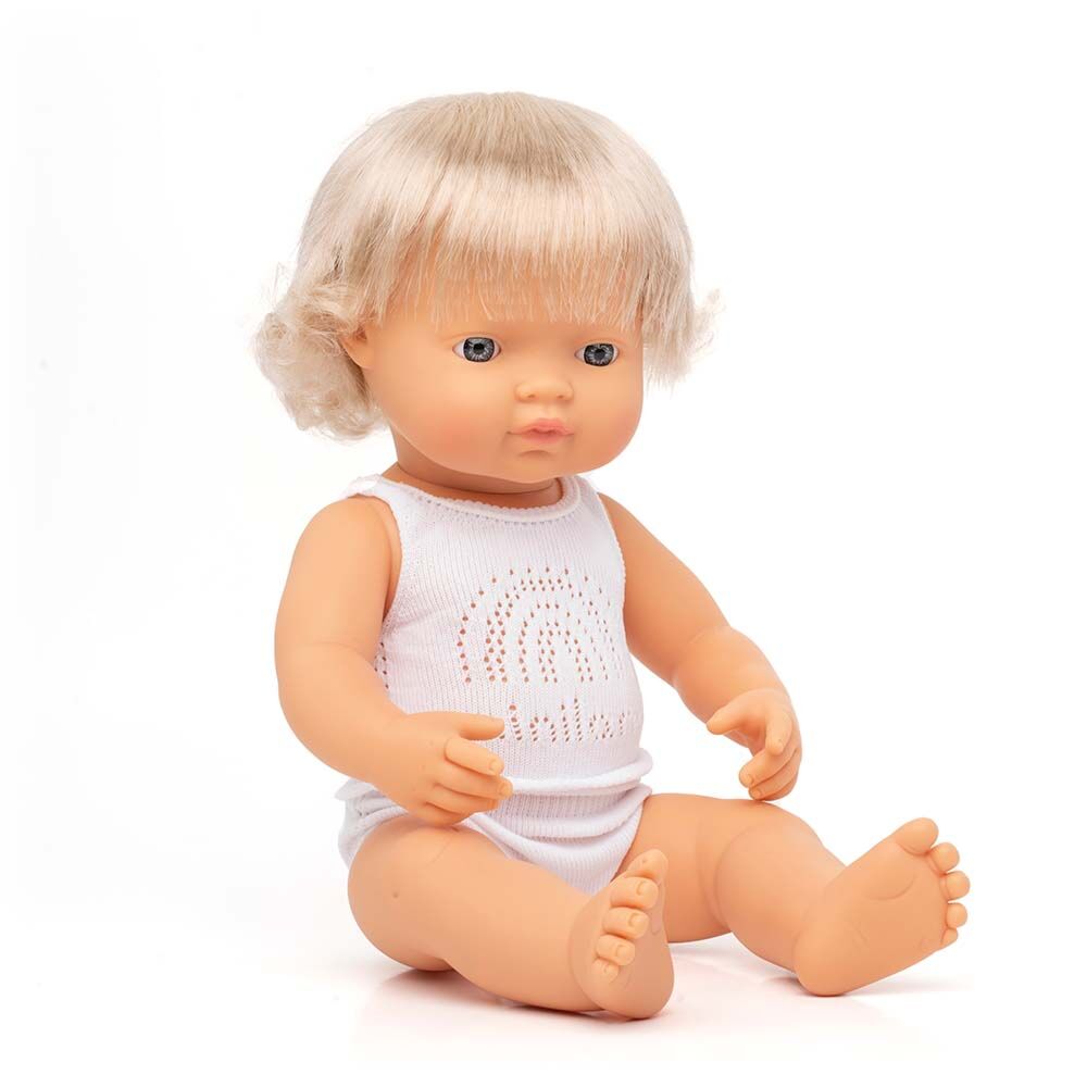 Boneco bebé Miniland Caucasiano de 38cm, com cabelo loiro e olhos azuis, sentado e a usar roupa interior branca com um padrão de arco-íris.