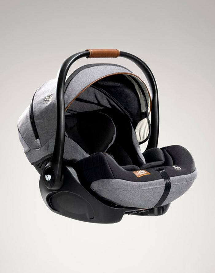 Cadeira auto i-Size com a base ISOFIX, vista ligeiramente de lado, destacando a posição da alça de transporte.