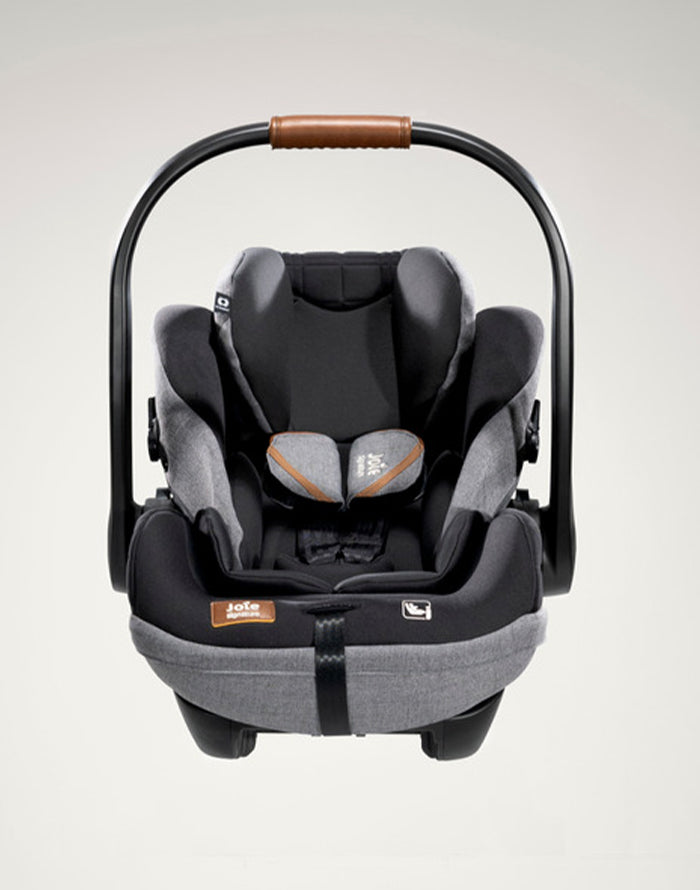 Vista frontal da cadeira auto i-Size, com a alça de transporte ajustada para trás, destacando o design ergonômico.