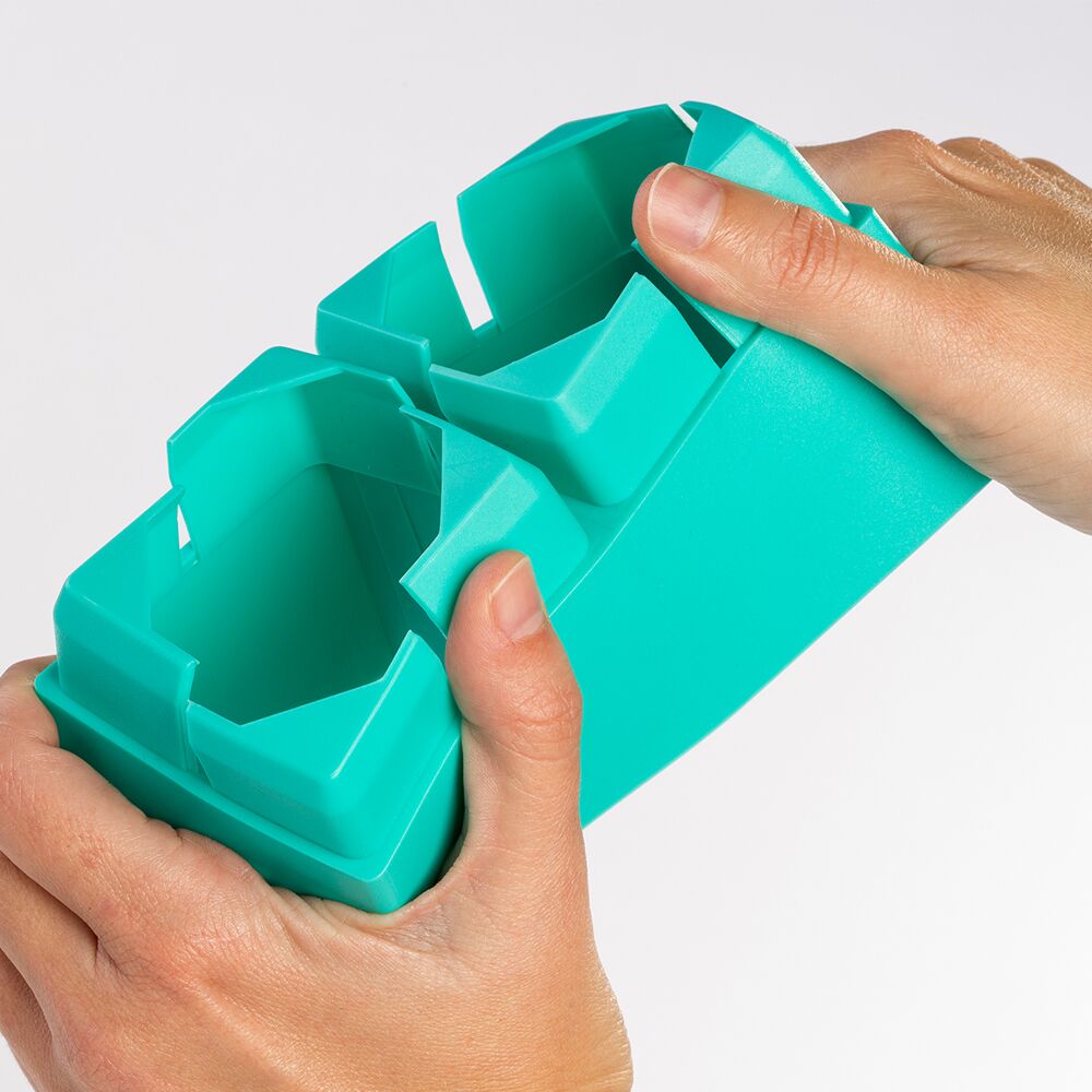 Detalhe de mãos a encaixar um bloco Miniland Eco Super Kim verde, mostrando a flexibilidade do bioplástico.