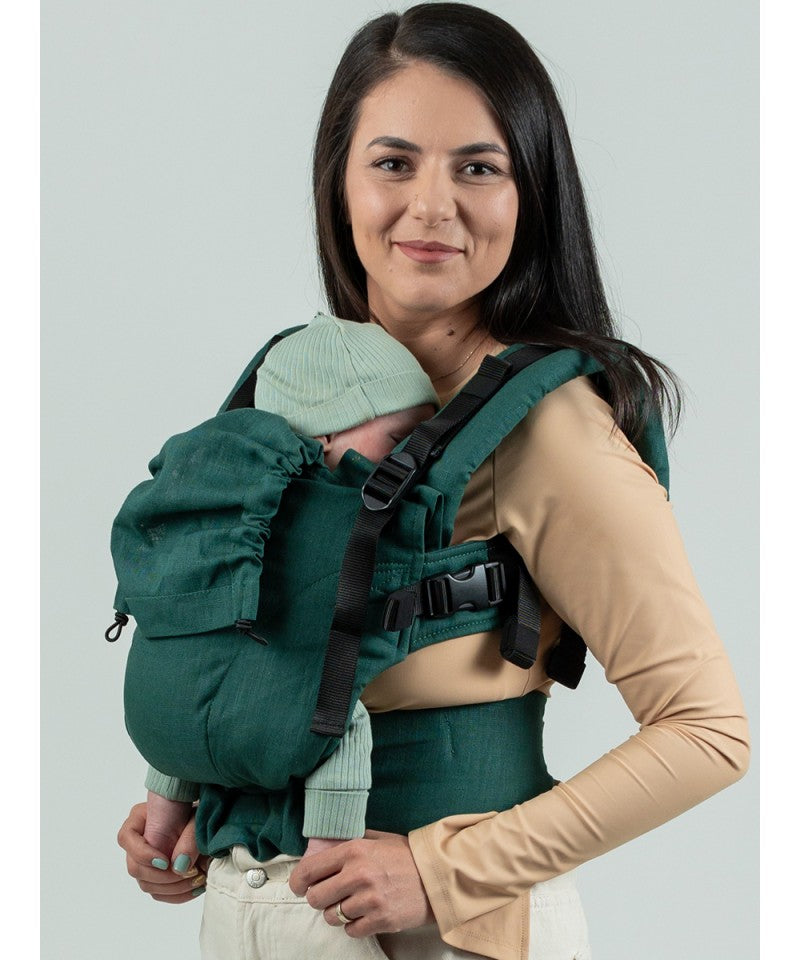 Mulher a usar a mochila Isara THE One Ajustável Evergreen Linen com um bebé recém-nascido na posição frontal, com a criança de frente para ela.