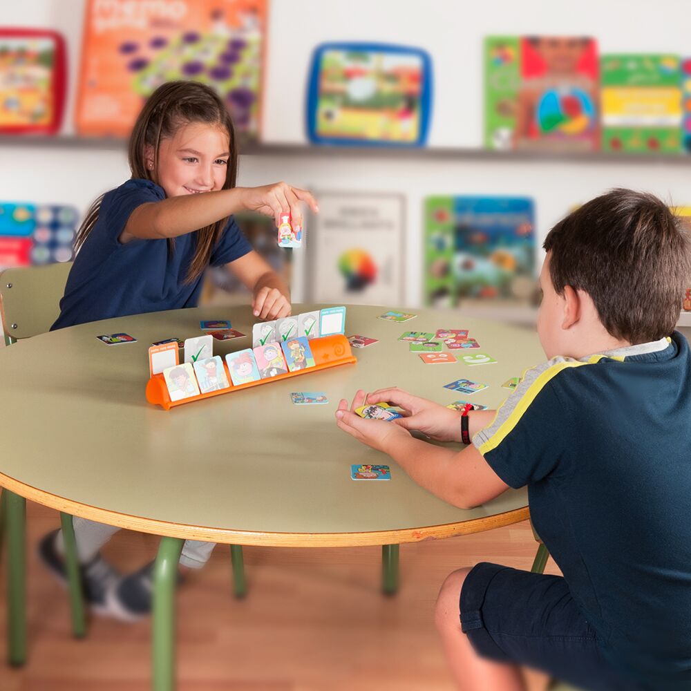 Duas crianças sentadas a uma mesa redonda a brincar com o Miniland Jogo Educativo de 36 Sequências Rotinas Diárias, com cartões de rotinas e um suporte laranja.