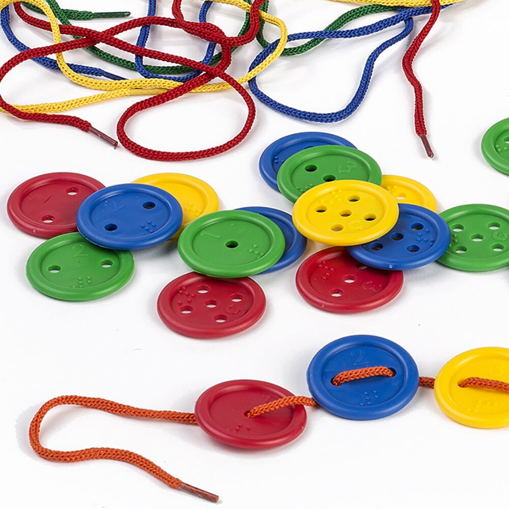 Botões Miniland coloridos com números e Braille, e cordões de enfiar espalhados, alguns botões já enfiados.