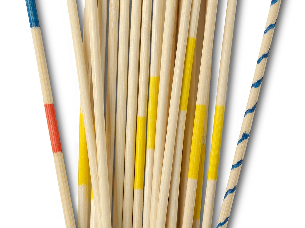 Detalhe aproximado dos paus de madeira do jogo Mikado, focando-se nas riscas coloridas vermelhas, amarelas e azuis.