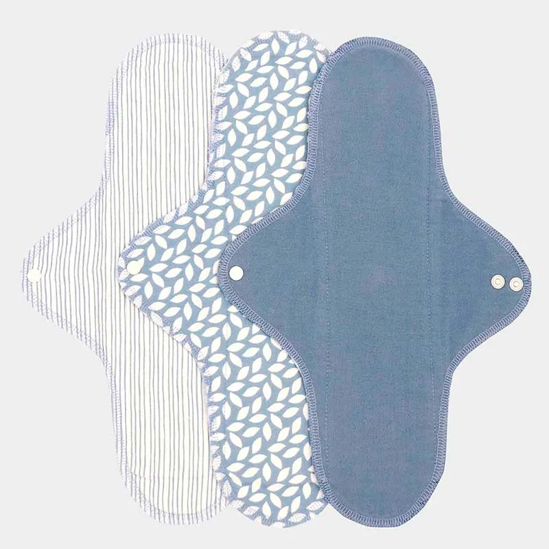 Conjunto de três pensos menstruais reutilizáveis ImseVimse para a noite, mostrando padrões de riscas, folhas e azul liso, feitos em algodão orgânico.