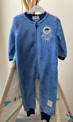 Macacão pijama Waterlemon azul de tecido polar pendurado num cabide, com padrão de peixes e um aplique de Esquimó.