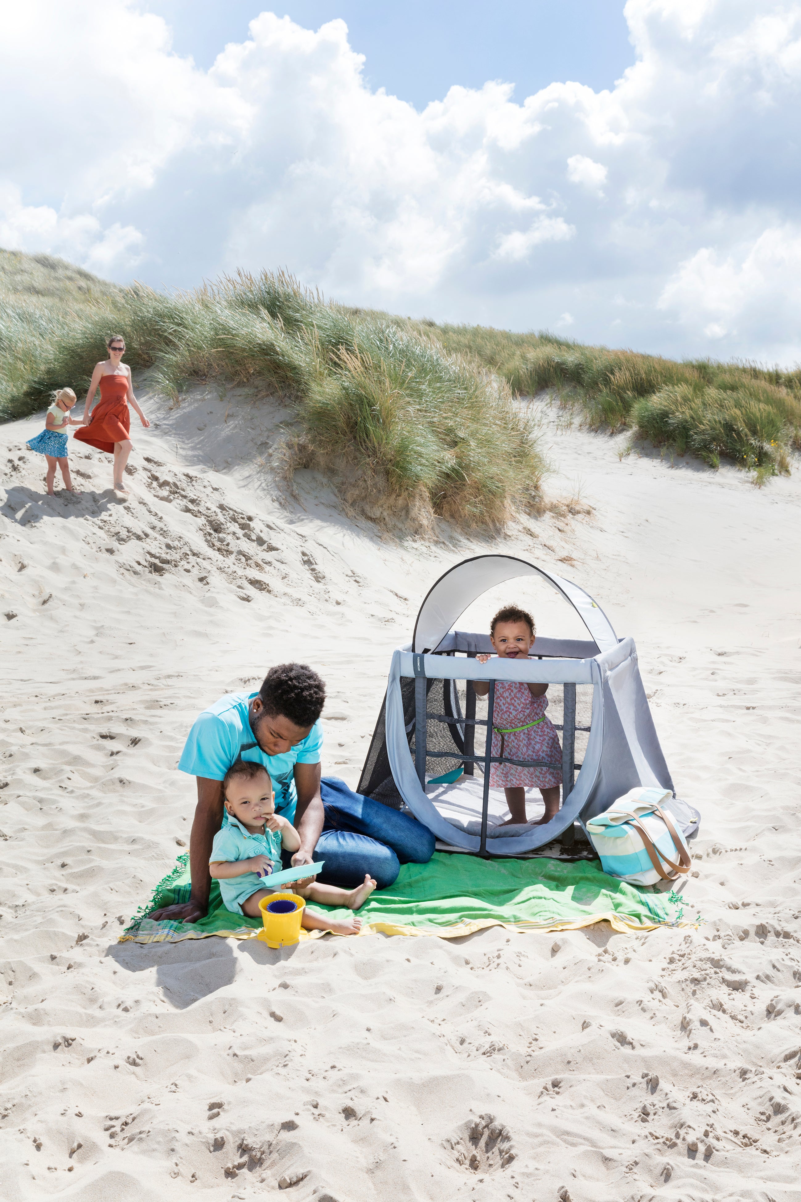 Cama de viagem Aeromoov montada, cinzenta, com bebé a dormir no nível superior, mostrando a facilidade de uso.