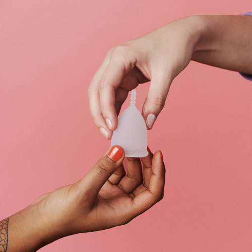 Detalhe das mãos a segurar o copo menstrual em silicone de grau médico AllMatters
