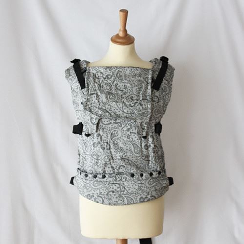 Porta-bebés ergonómico com padrão paisley cinzento, apresentado num manequim, pronto para aluguer.