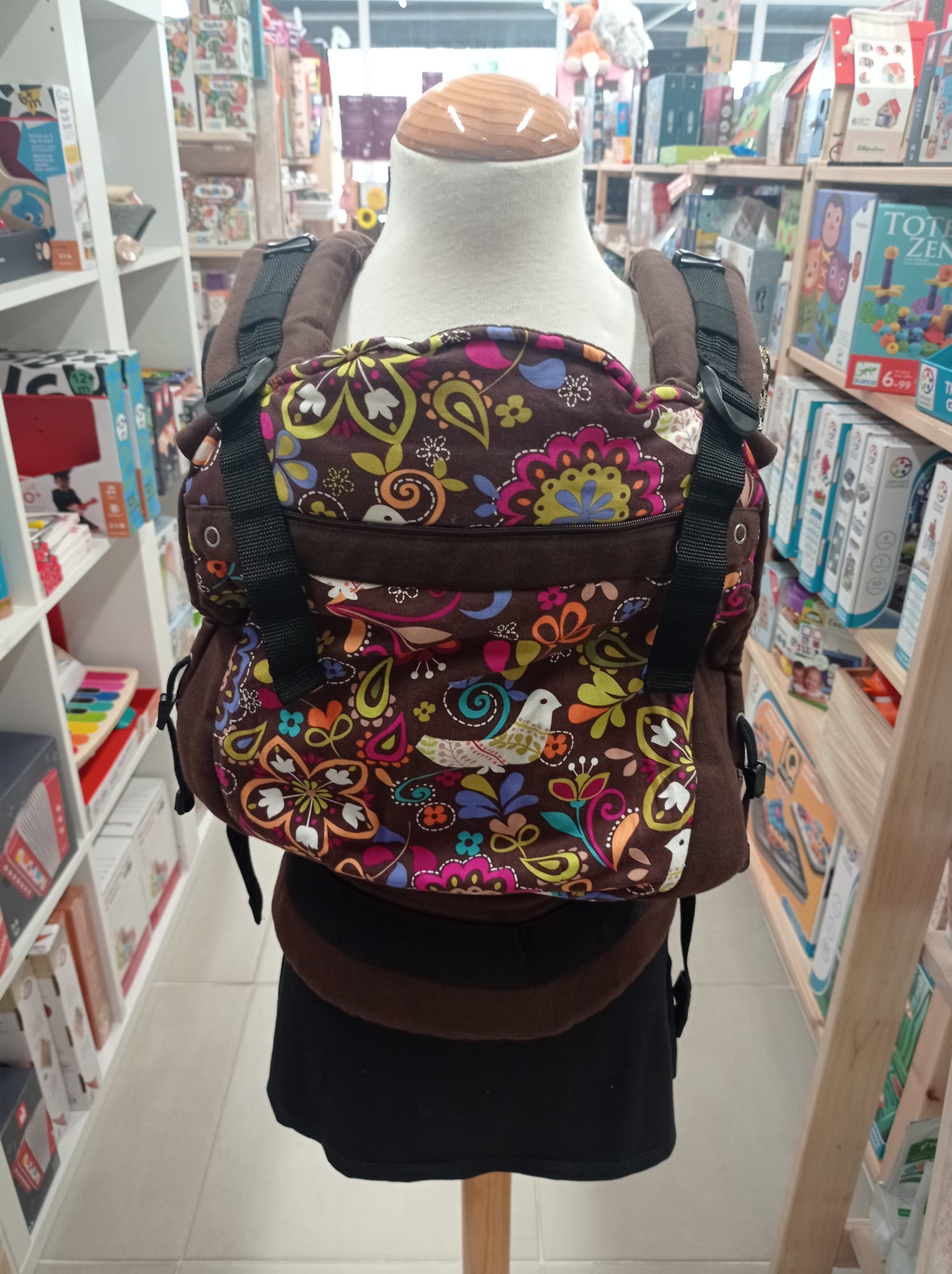 Detalhe de um porta-bebés ergonómico alugado, focando a fivela e o tecido de suporte, evidenciando a qualidade para teste.