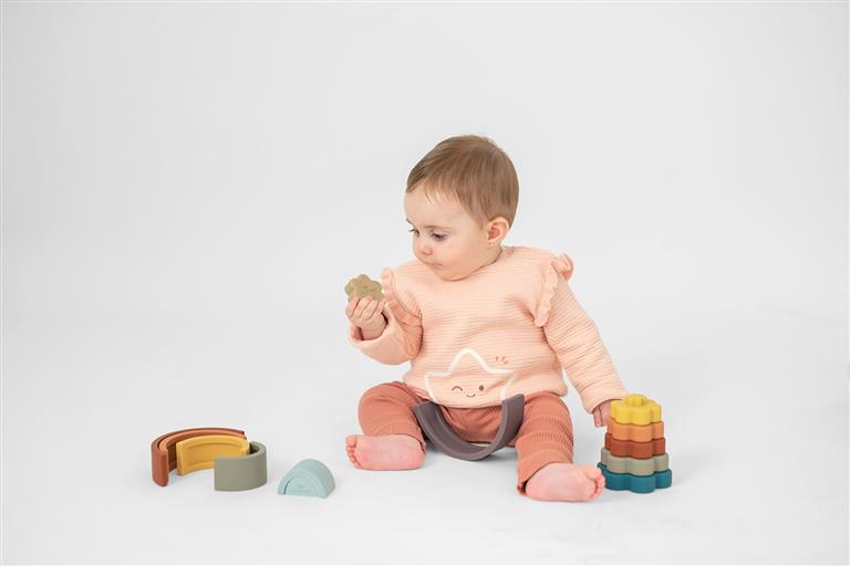Bebé a brincar com o arco-íris de silicone Olmitos, mostrando a interação do brinquedo com a criança e o seu tamanho adequado para as mãos pequenas.
