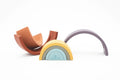 As peças do arco-iris de silicone Olmitos espalhadas numa superfície branca, mostrando a flexibilidade do material e as diferentes formas das peças.