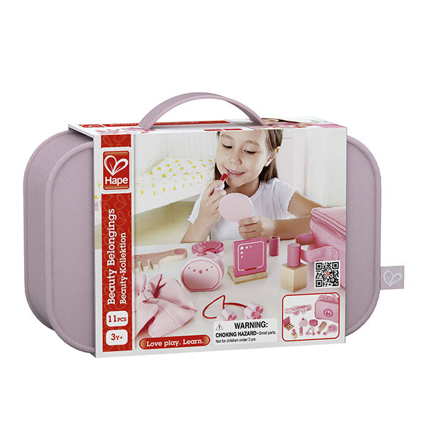 Embalagem do Hape Nécessaire com acessórios de maquilhagem, mostrando uma menina a aplicar batom de brincar e todos os 11 acessórios de madeira e tecido.