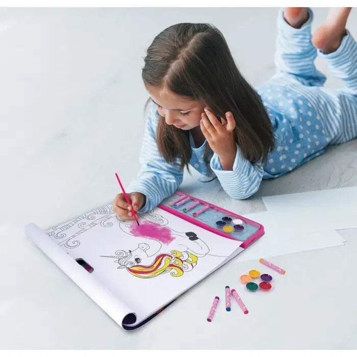Criança de pijama a colorir um unicórnio num bloco gigante com aguarelas, demonstrando o uso do kit de atividades.