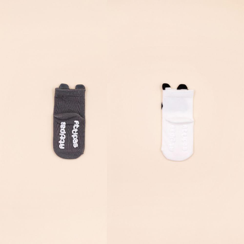 Meias Attipas cinzentas com texto Attipas em relevo na sola e meias brancas com o mesmo detalhe, vistas de costas.