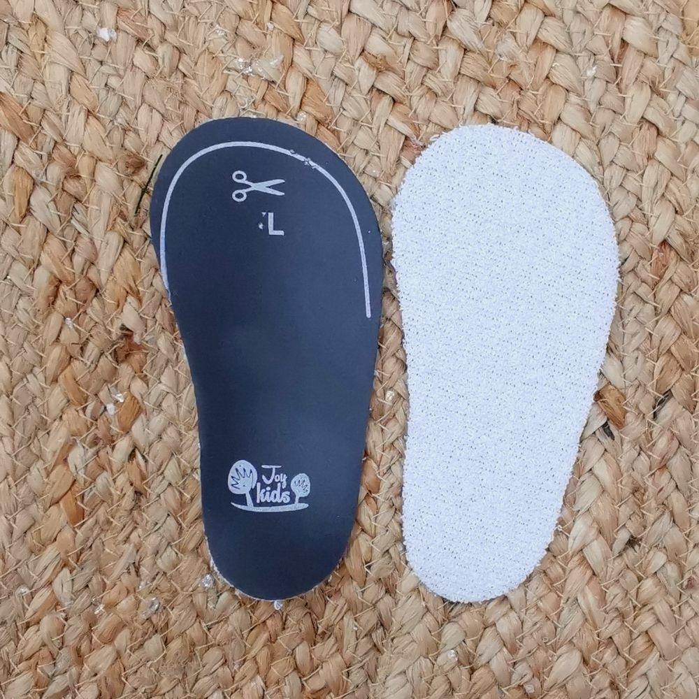 Palmilha Attipas tamanho L, vista de cima (lado branco felpudo) e de baixo (lado preto com marcação de corte e logo Joy Kids), sobre fundo de fibra natural.