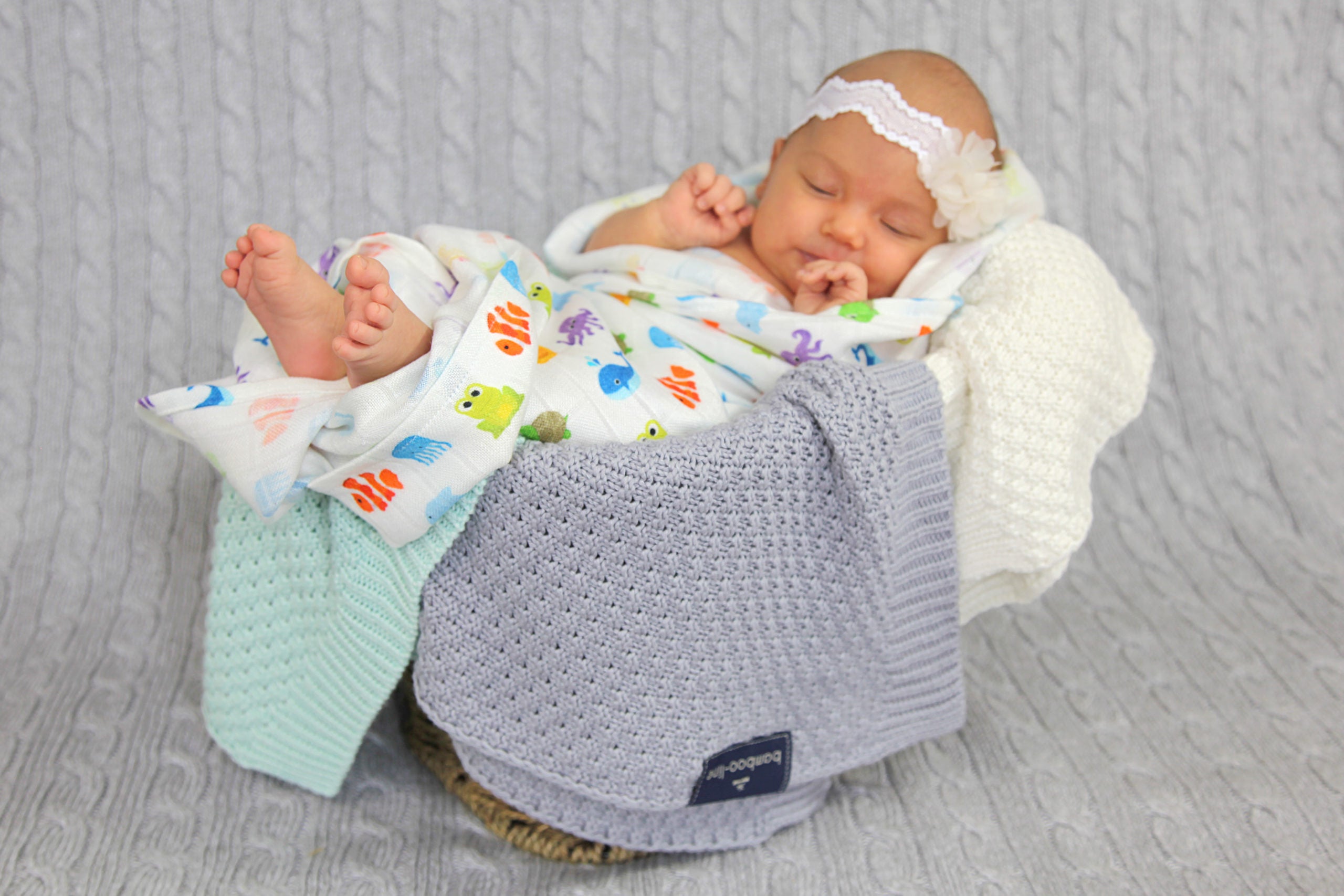 Imagem de lifestyle: um bebé aconchegado confortavelmente sob a manta cinza Bamboo Line, destacando a respirabilidade e suavidade.