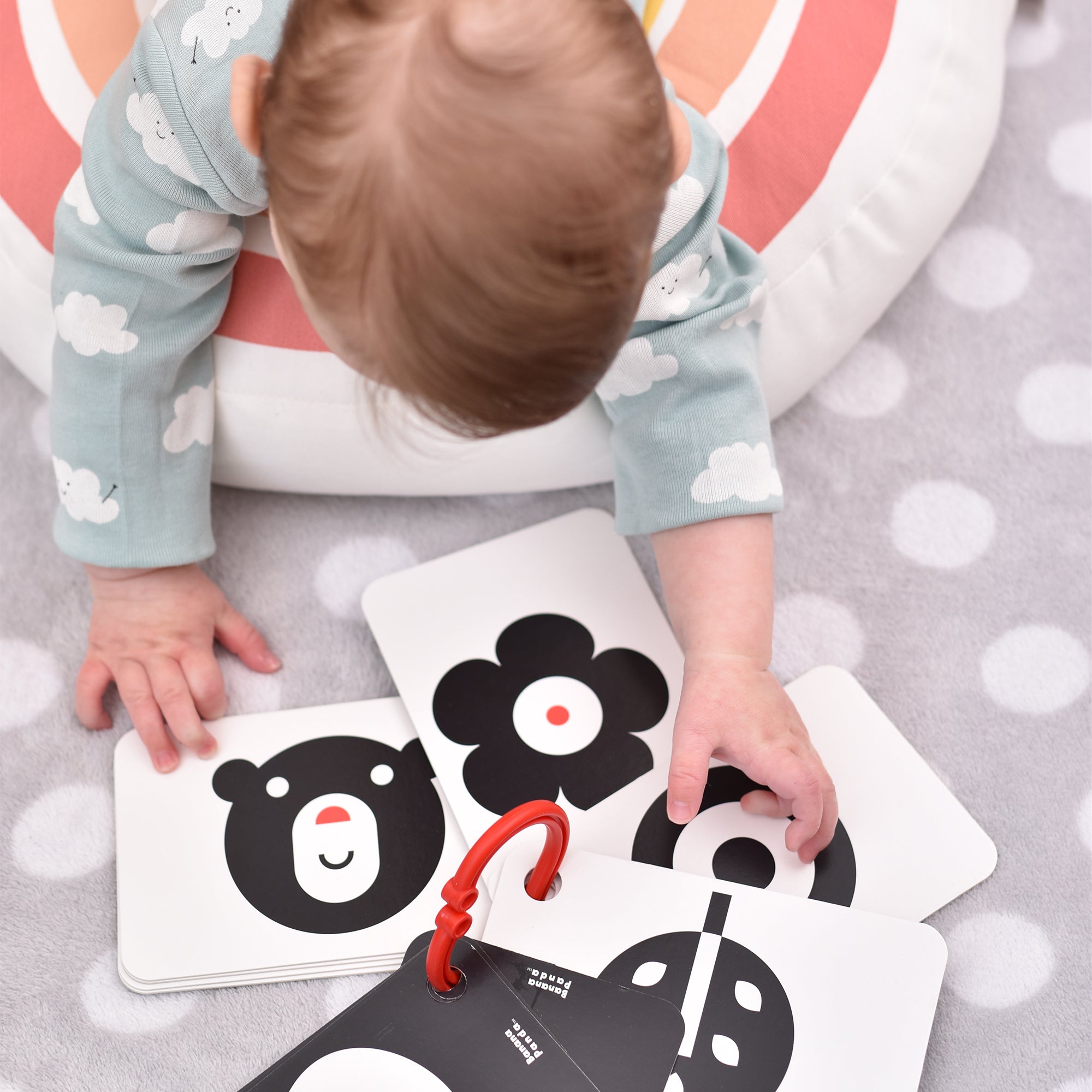 Detalhe dos cartões de alto contraste Banana Panda, mostrando a argola de plástico robusta incluída para pendurar no berço ou carrinho.