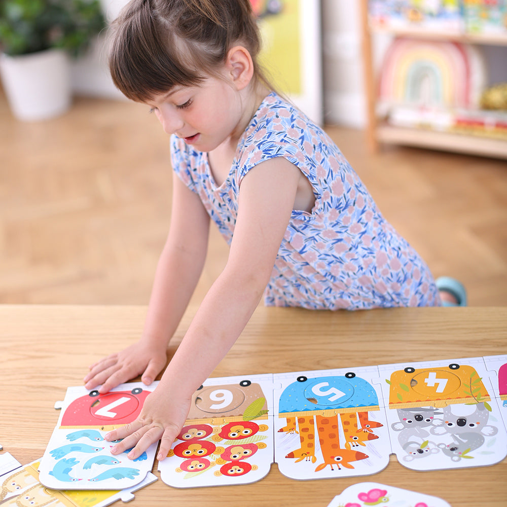 Peças soltas do puzzle: 10 círculos de partida numerados (1 a 10) e 20 peças de comboio com animais.