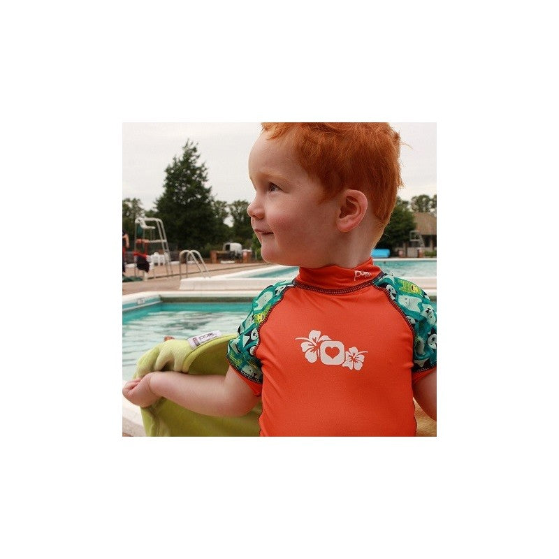 Bebé a usar fato de surf com proteção solar perto de uma piscina.