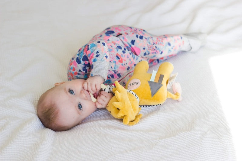 Bebé a brincar com o peluche leão Tikiri orgânico.