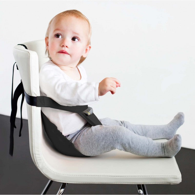 Bebé sentado numa cadeira de adulto usando o arnês Minimonkey preto
