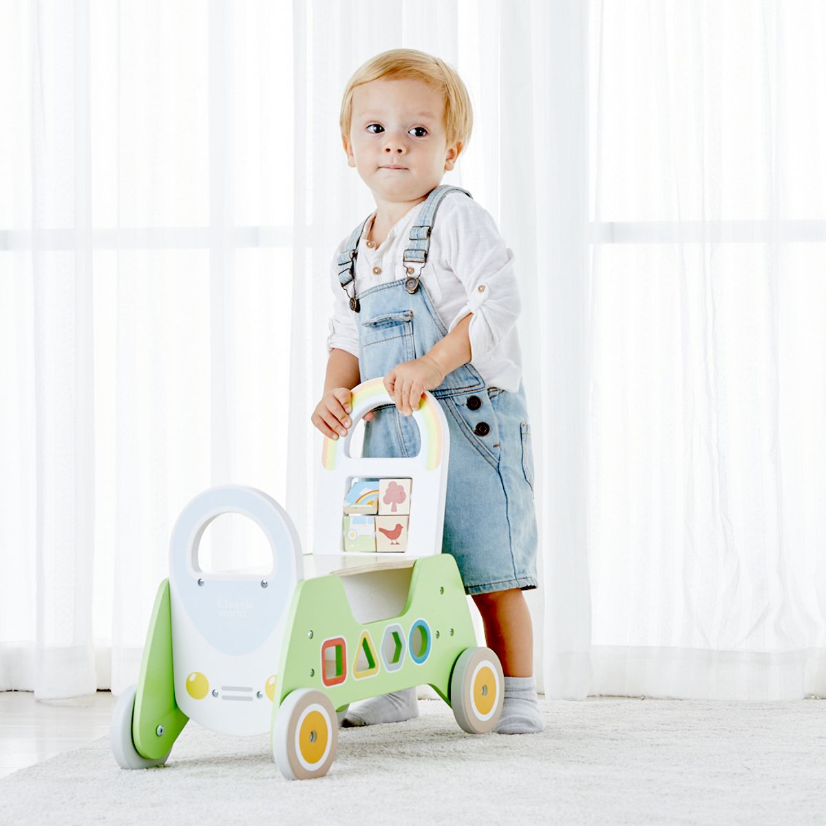 Menino usando o andador 2 em 1 da Classic World para aprender a andar, com o apoio da pega traseira em arco-íris.