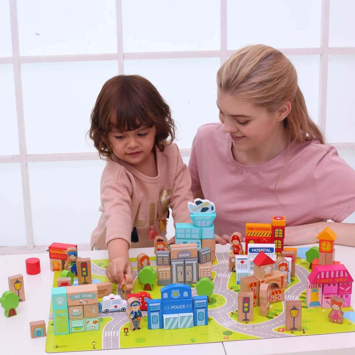 Detalhe do conjunto Classic World Blocos de Construção 'Cidade' com uma criança a brincar com os blocos e o tapete de base.