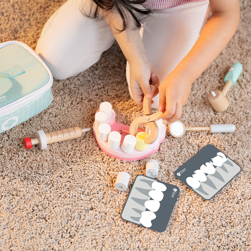 Criança a brincar com o Classic World Conjunto de Dentista, utilizando a pinça para remover um dente.
