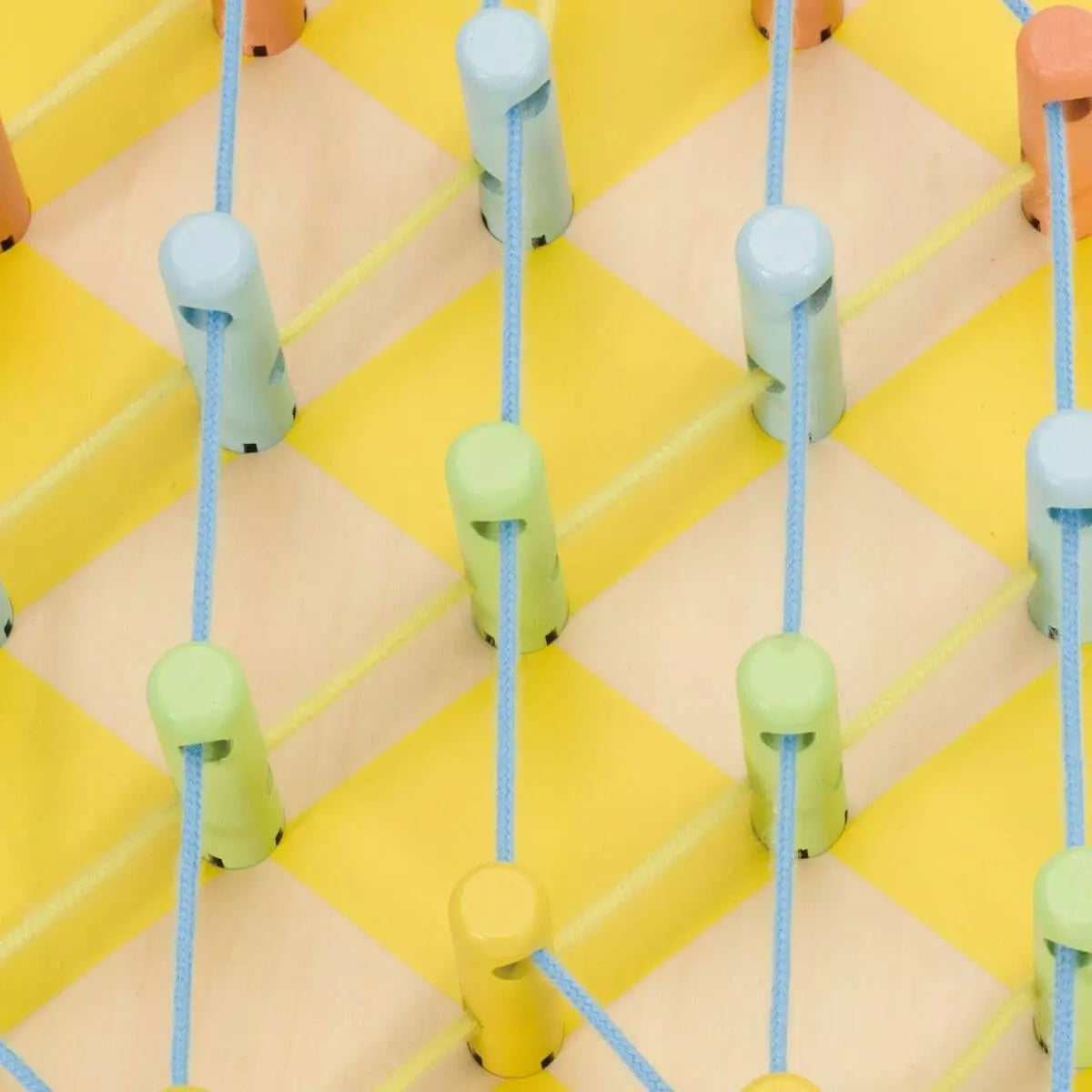 Detalhe dos pinos coloridos e dos fios no jogo de enfiamento Abacaxi, mostrando a textura dos materiais e a possibilidade de criar padrões.