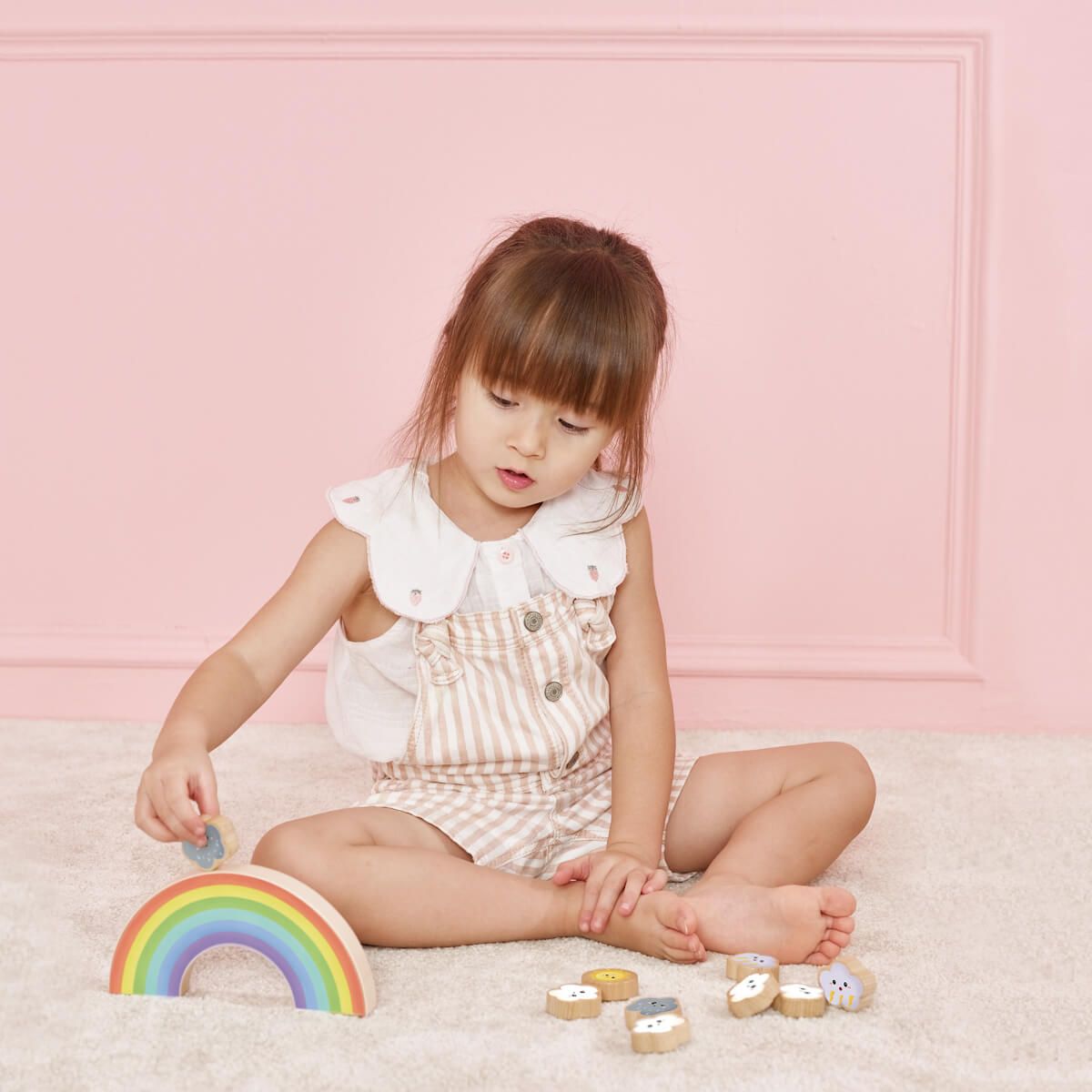 Menina brincando com o jogo de equilíbrio Classic World Arco Íris, desenvolvendo habilidades motoras e coordenação olho-mão.