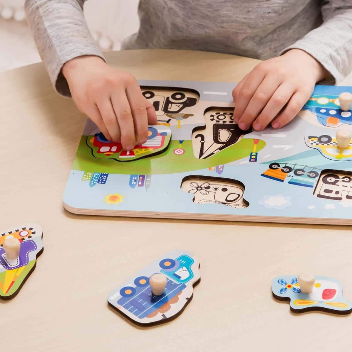 Criança a brincar com o puzzle de madeira Classic World com 8 peças de veículos. Desenvolvimento infantil.