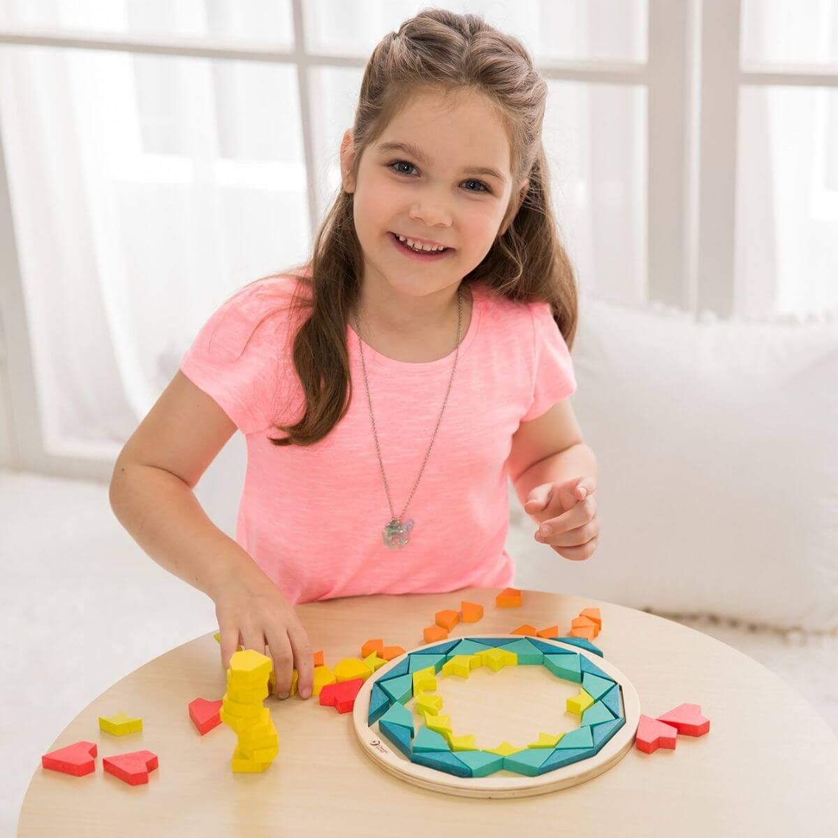 Criança sorrindo enquanto brinca com o Puzzle Mandala Classic World, criando um padrão circular.