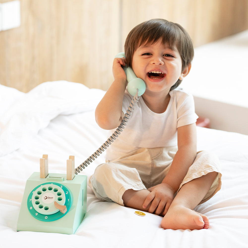Menino sorrindo enquanto brinca ao telefone com o telefone vintage Classic World.