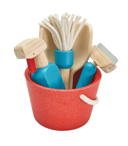 Detalhe do conjunto de limpeza PlanToys dentro do balde vermelho, mostrando a textura da madeira e os detalhes dos utensílios.