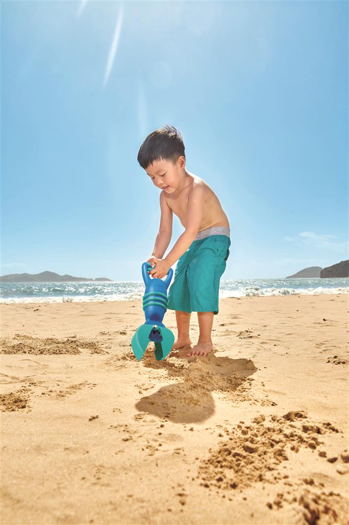 Criança a brincar na areia da praia com o agarrador da Hape, demonstrando o uso do brinquedo.