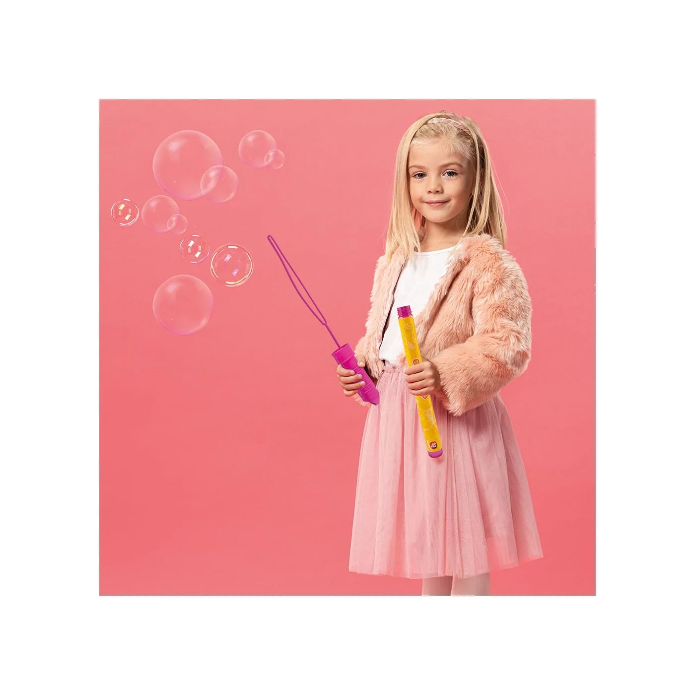 Criança sorridente a brincar com a espada de bolhas de sabão cor-de-rosa, com bolhas a flutuar no ar, ideal para diversão ao ar livre.