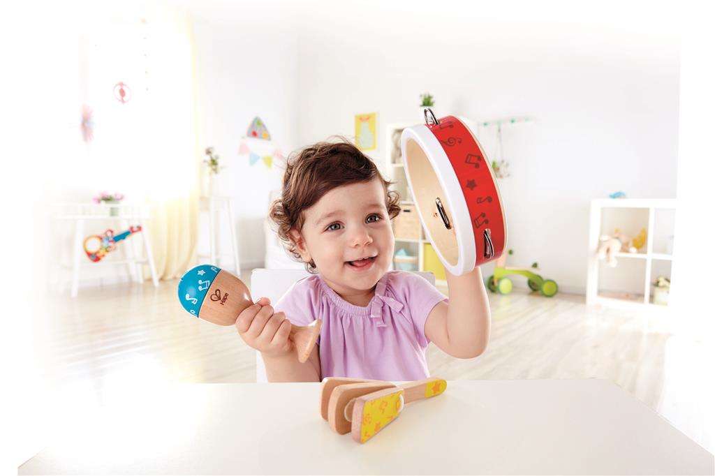 Criança feliz a tocar pandeireta e maraca da Hape