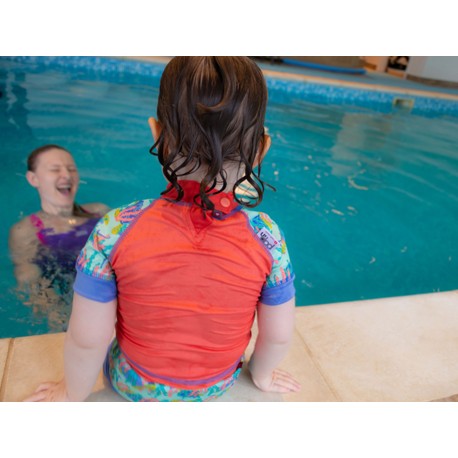 Vista traseira de criança na piscina com camisola de proteção solar