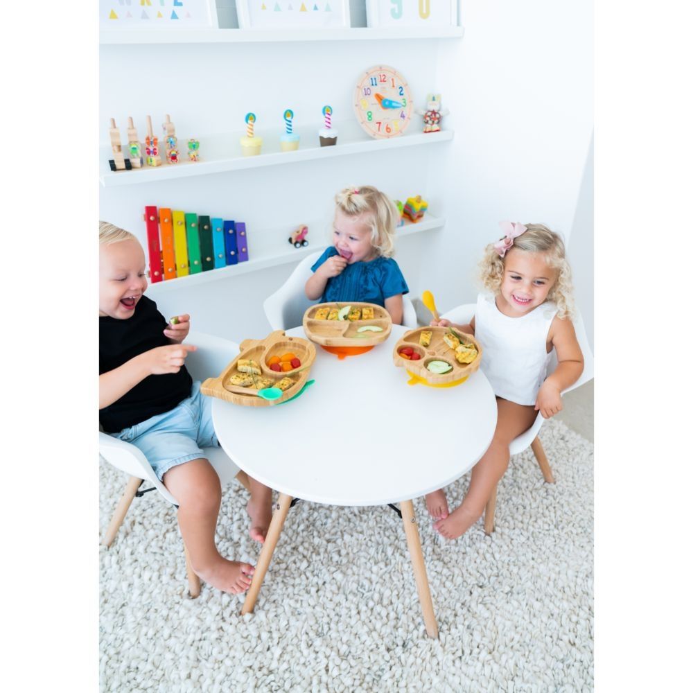 Três crianças a comer em pratos Eco Rascals numa mesa pequena.
