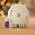 Difusor de óleos essenciais em forma de mocho branco da Young Living ao lado de um frasco de óleo de lavanda.