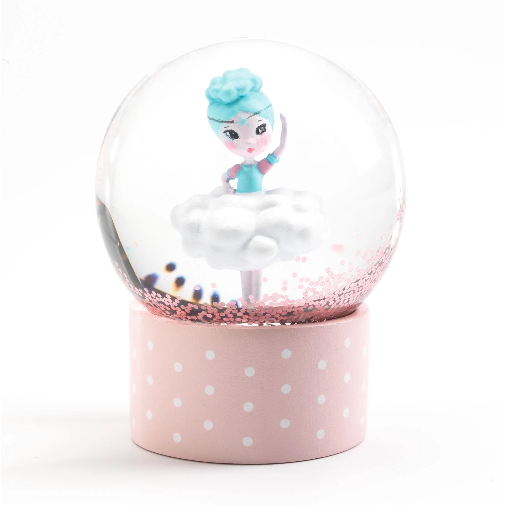 Close-up do mini globo de neve Djeco com uma bailarina em cima de uma nuvem, sobre base rosa com bolinhas brancas.