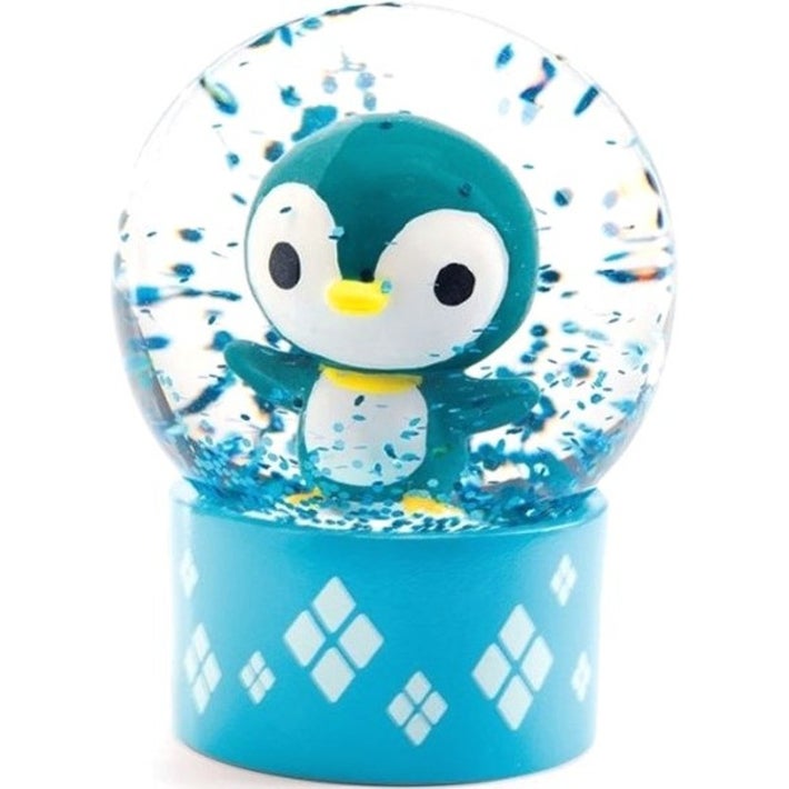 Detalhe do mini globo de neve com o pinguim azul-esverdeado sobre base azul clara com padrão de losangos.
