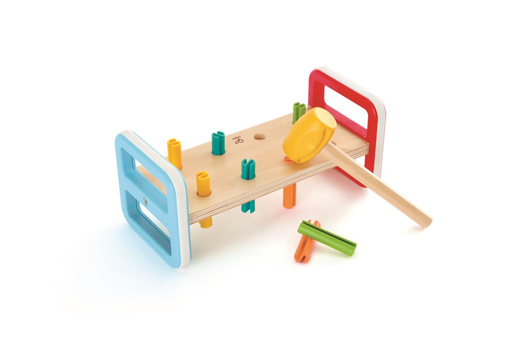Jogo do martelo da Hape em madeira colorida, com o martelo amarelo pousado sobre a bancada e alguns pinos já martelados, sobre um fundo branco.