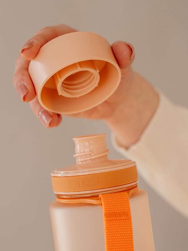 Comparação de escala da garrafa Equa Tritan Sunrise Laranja ao lado de outros objetos (ex: telemóvel) para ilustrar os 600ml de volume.