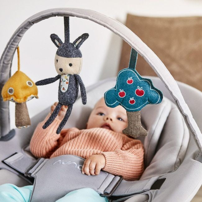 Arco de jogos Nuna encaixado na espreguiçadeira Leaf, exibindo brinquedos suspensos e design moderno.