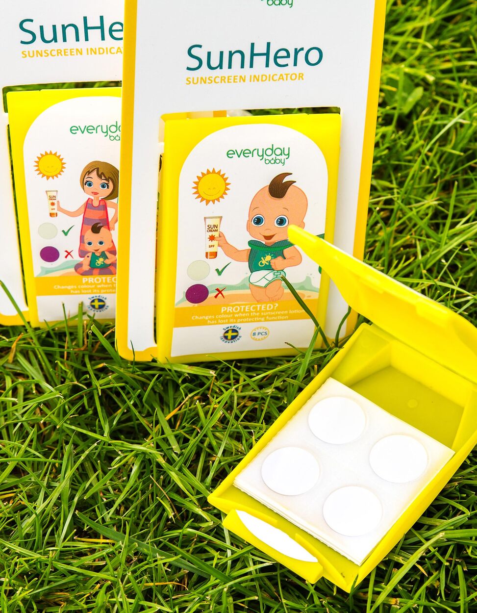 Everyday Baby SunHero, adesivos indicadores de proteção solar para bebés na relva com embalagem aberta.