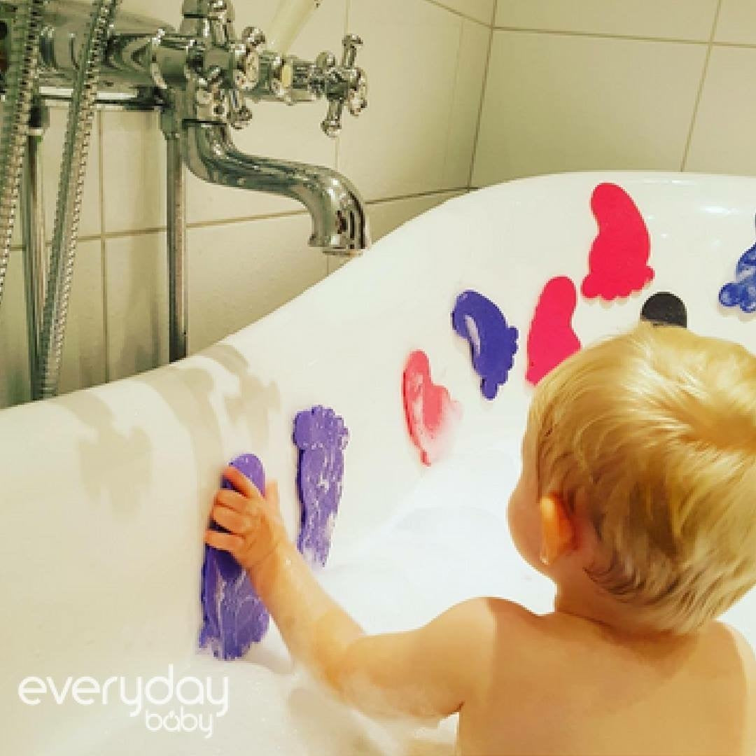 Criança a brincar com os Everyday Baby WaterHero pezinhos antiderrapantes colados na parede da banheira.